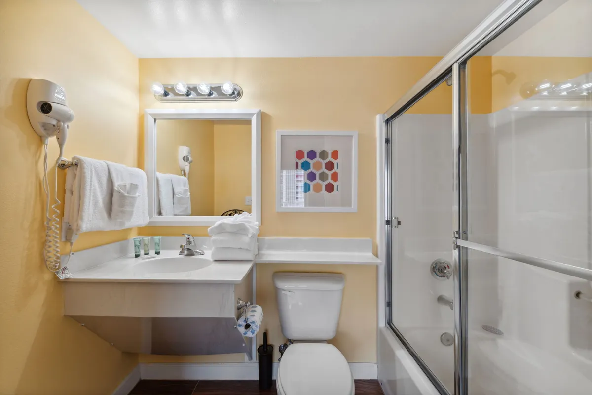A fresh, vibrant bathroom with a mirror above the sink, colorful artwork, and neatly arranged towels, creating an inviting space for personal care and relaxation after a day of excitement.