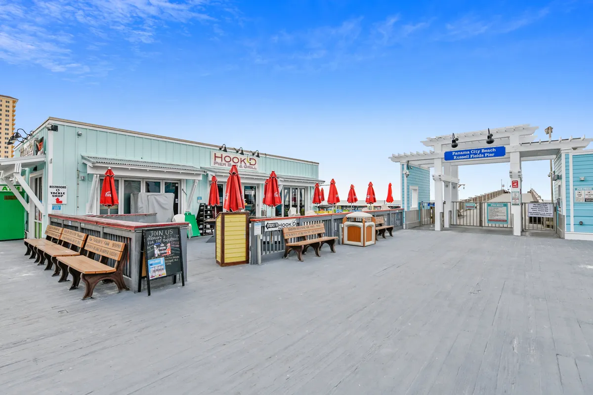 A cheerful restaurant exterior with red umbrellas, a welcoming sign, and a casual outdoor dining area just steps from the resort. The lively atmosphere hints at the vibrant local dining and nightlife scene on South Thomas Drive.